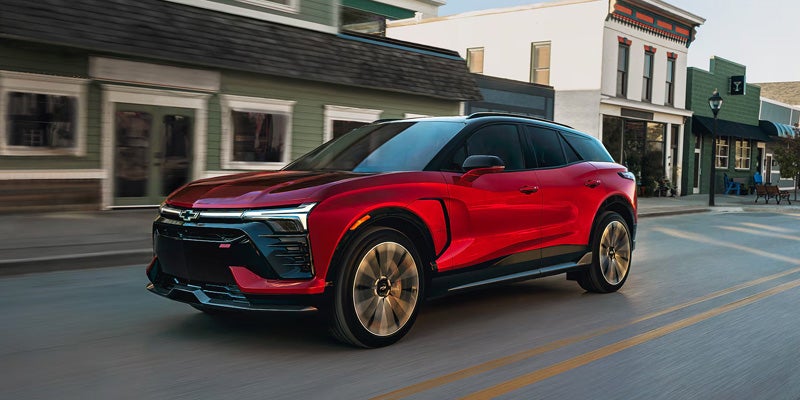 A red 2026 Chevy Blazer EV drives throughout a downtown city street
