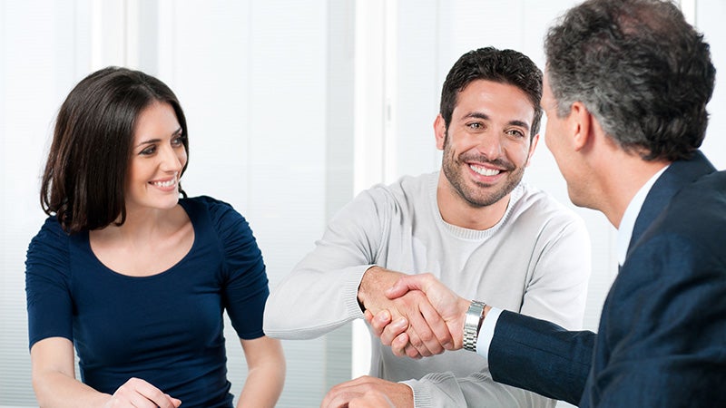 Image of a couple signing document and handshaking with the finance person