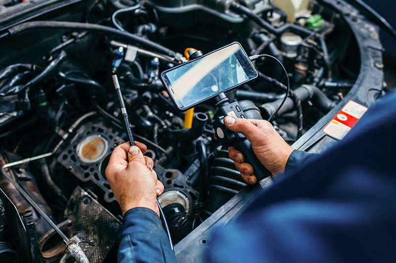 Image of a man inspecting the engine with the device connected to the phone