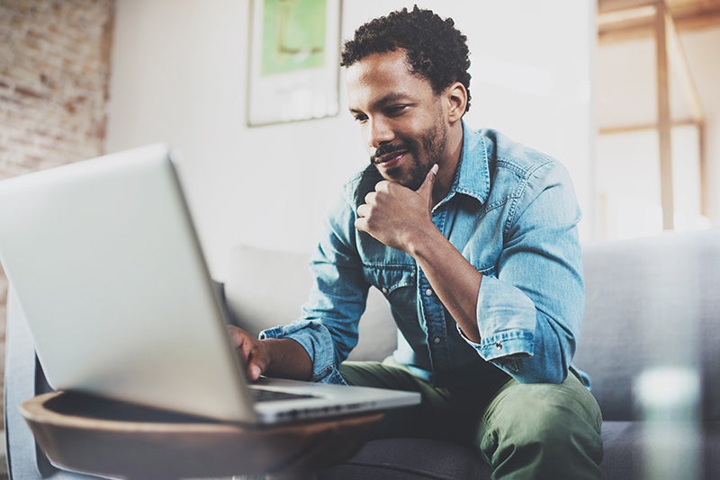 Image of a man smiling and searching new cars in laptop
